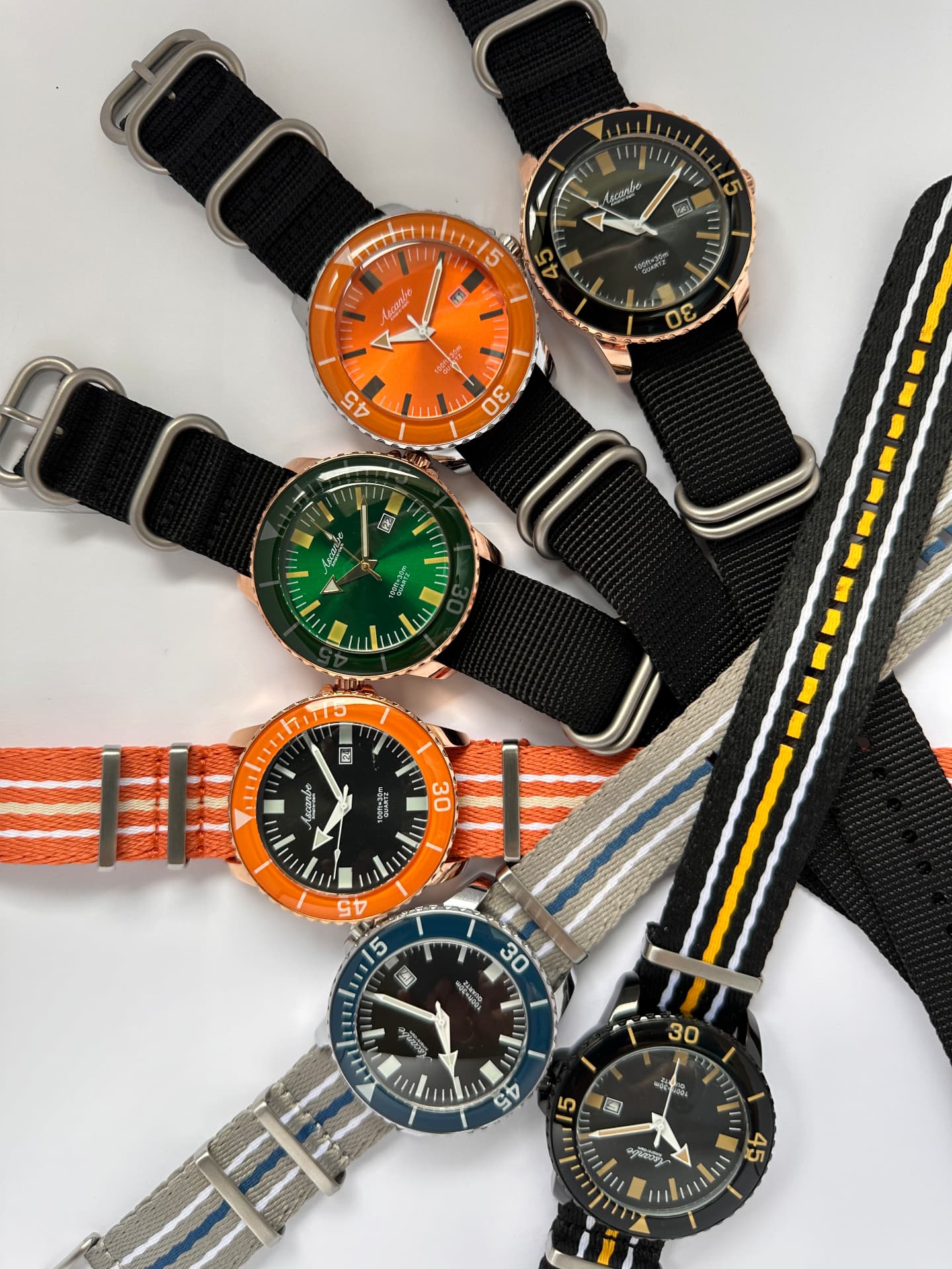 A group of Ascanbe divers in different dial colours with fabric straps