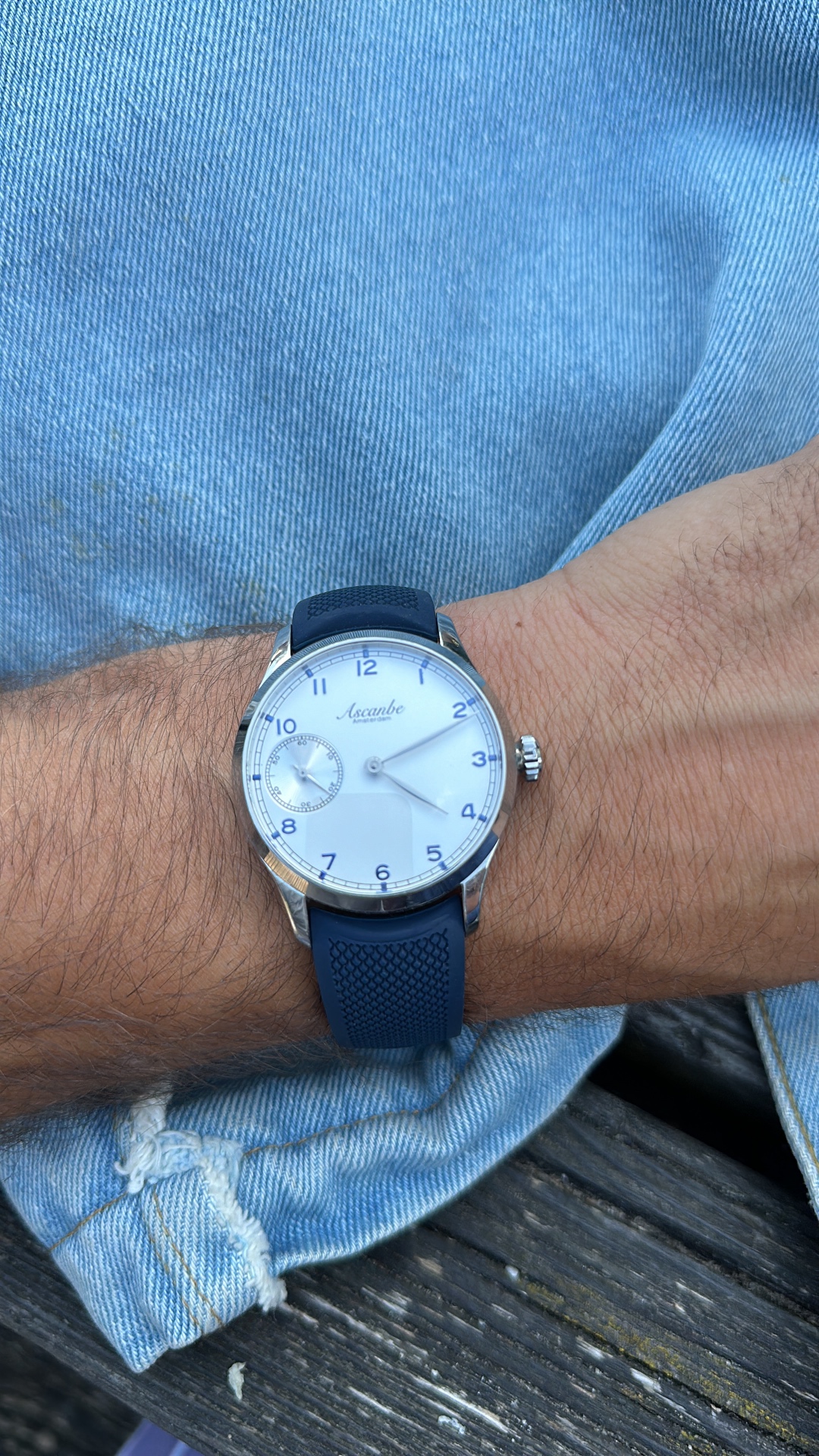 A white Ascanbe watch with small seconds and a blue strap